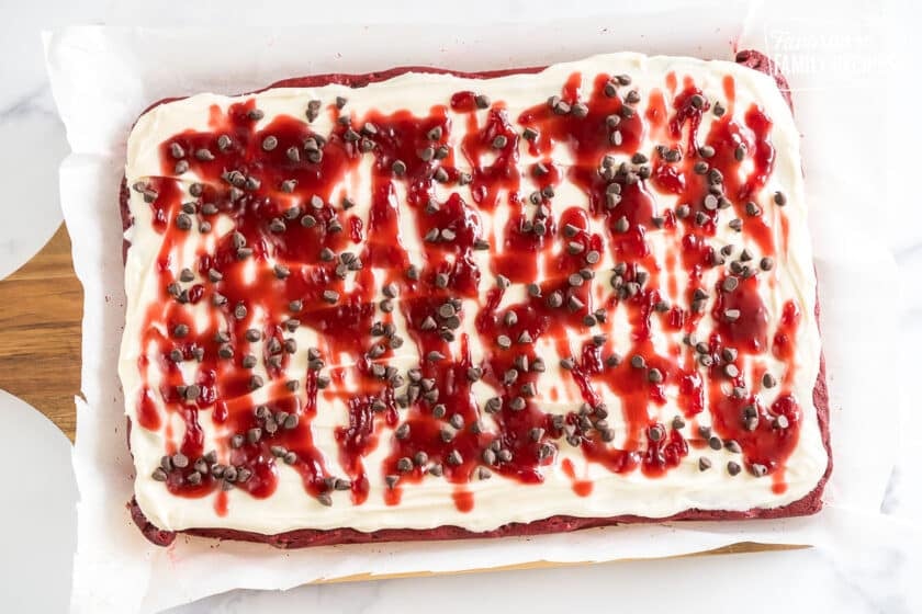 Red Velvet Brownies frosted with cream cheese icing and topped with raspberry topping and chocolate chips