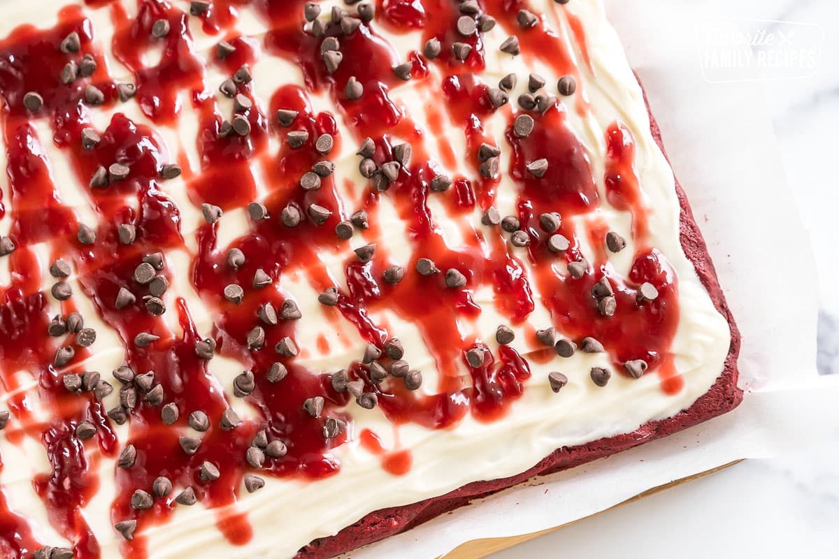 Red Velvet Brownies frosted with cream cheese icing and topped with raspberry topping and chocolate chips