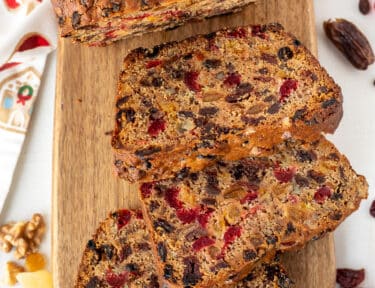Three slices of Fruit Cake on a cutting board.
