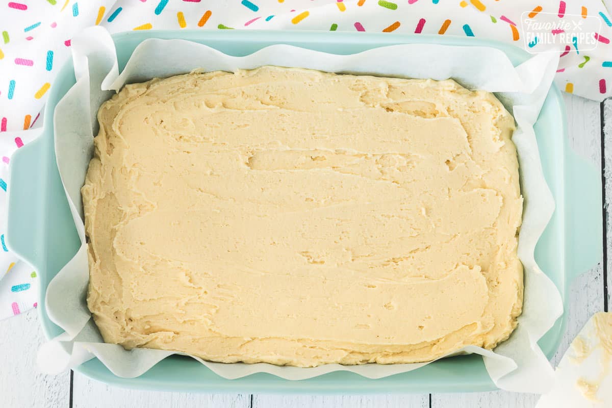Baking dish lined with parchment paper and smoothed Sugar Cookie Bar dough.