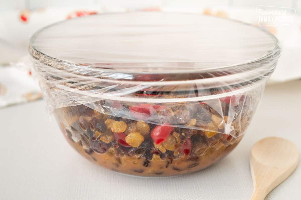 Covered mixing bowl with soaking dried fruit in orange juice.