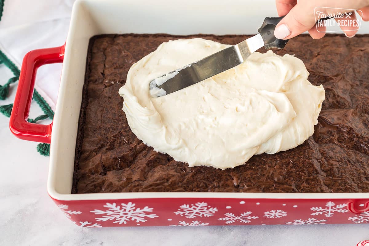 Spreading White chocolate frosting on cooled brownies.