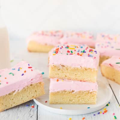 Stacked Sugar Cookie Bars on a plate with sprinkles. Milk on the side.