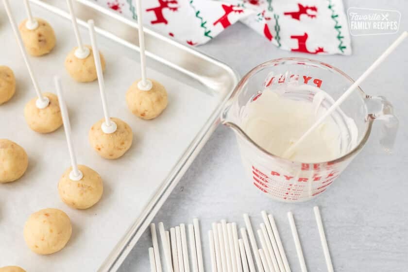 Lollipop sticks dipped in white chocolate and placed into cake balls to make Christmas cake pops