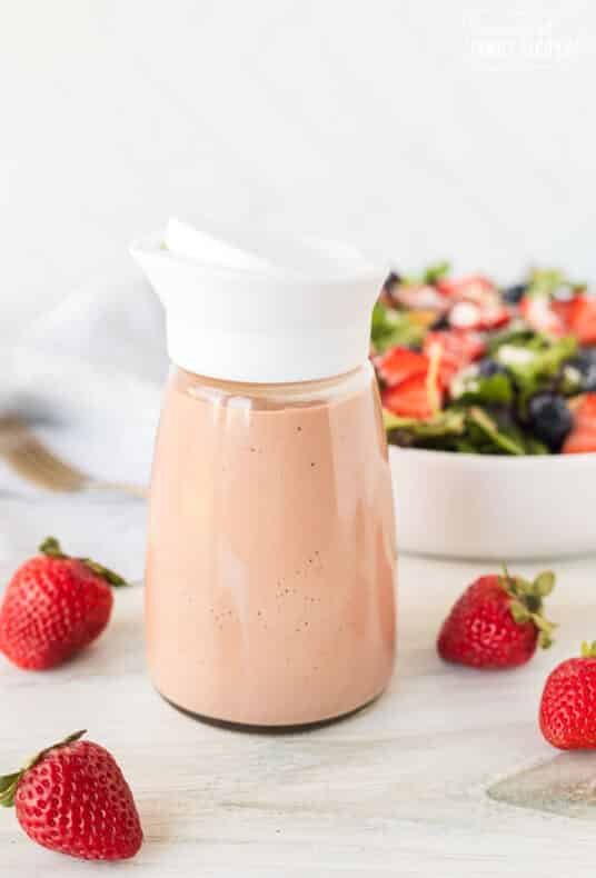 Jar of Strawberry Vinaigrette in front of a salad.