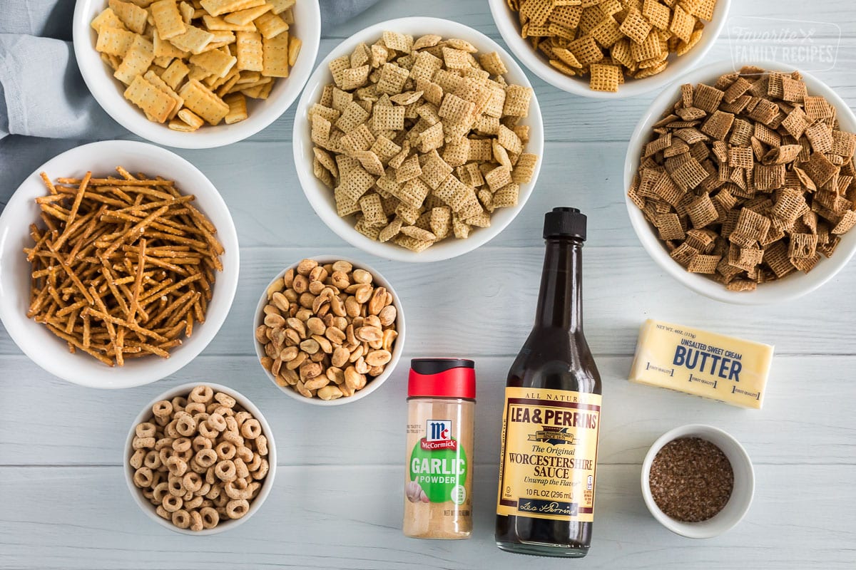 Ingredients for chex mix including, corn chex, wheat chex, rice chex, pretzel sticks, cheerios, mini club crackers, peanuts, garlic powder, seasoning salt, worcestershire sauce, and butter.