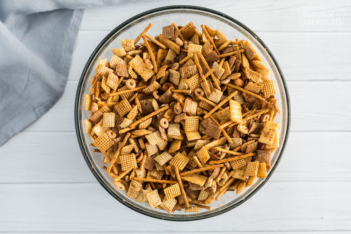 A bowl of chex mix that has been stirred and mixed with seasoning sauce.