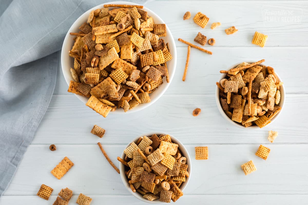 Three bowls of chex mix on a table