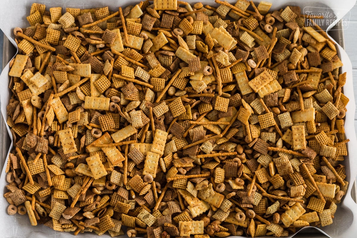 Chex mix laid on a pan with parchment paper.
