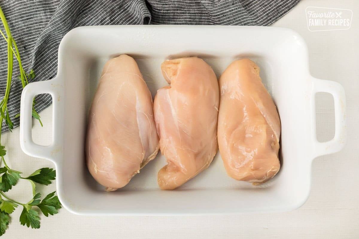 Baking dish with three boneless skinless chicken breasts.