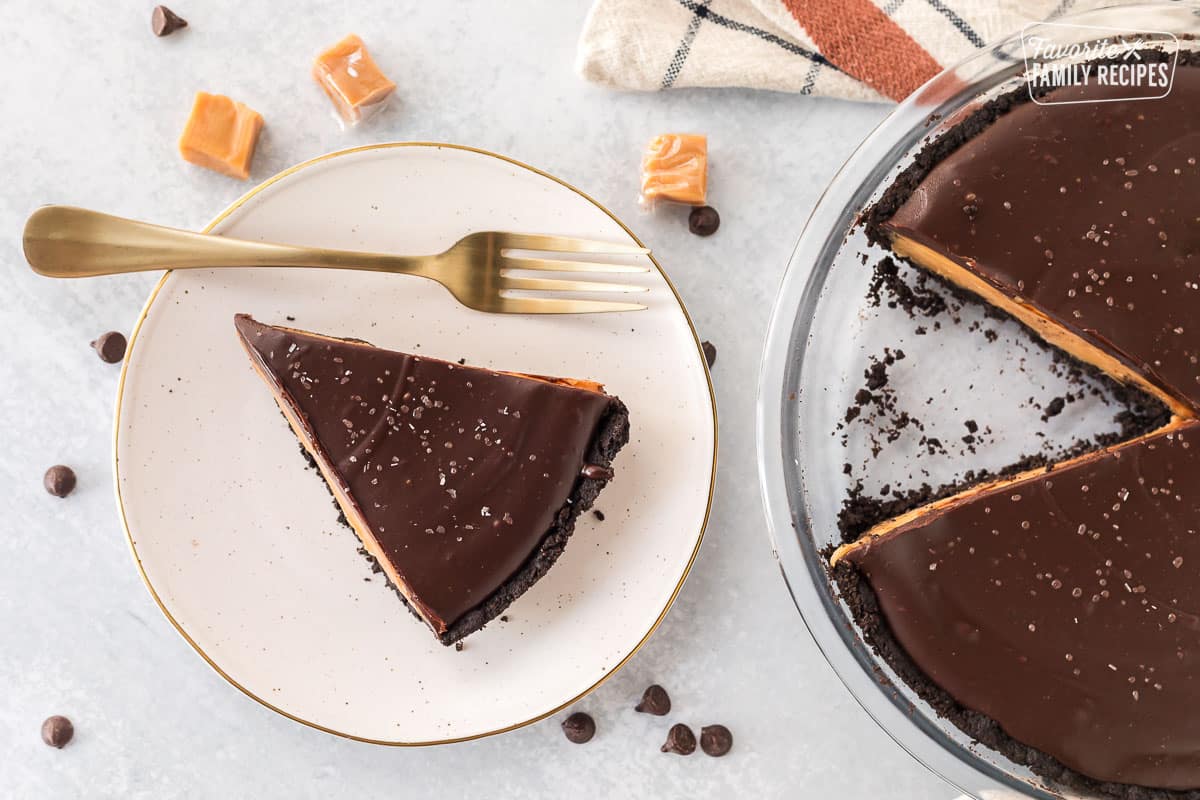 Slice of Salted Caramel Pie on a plate with a fork next to the whole pie.