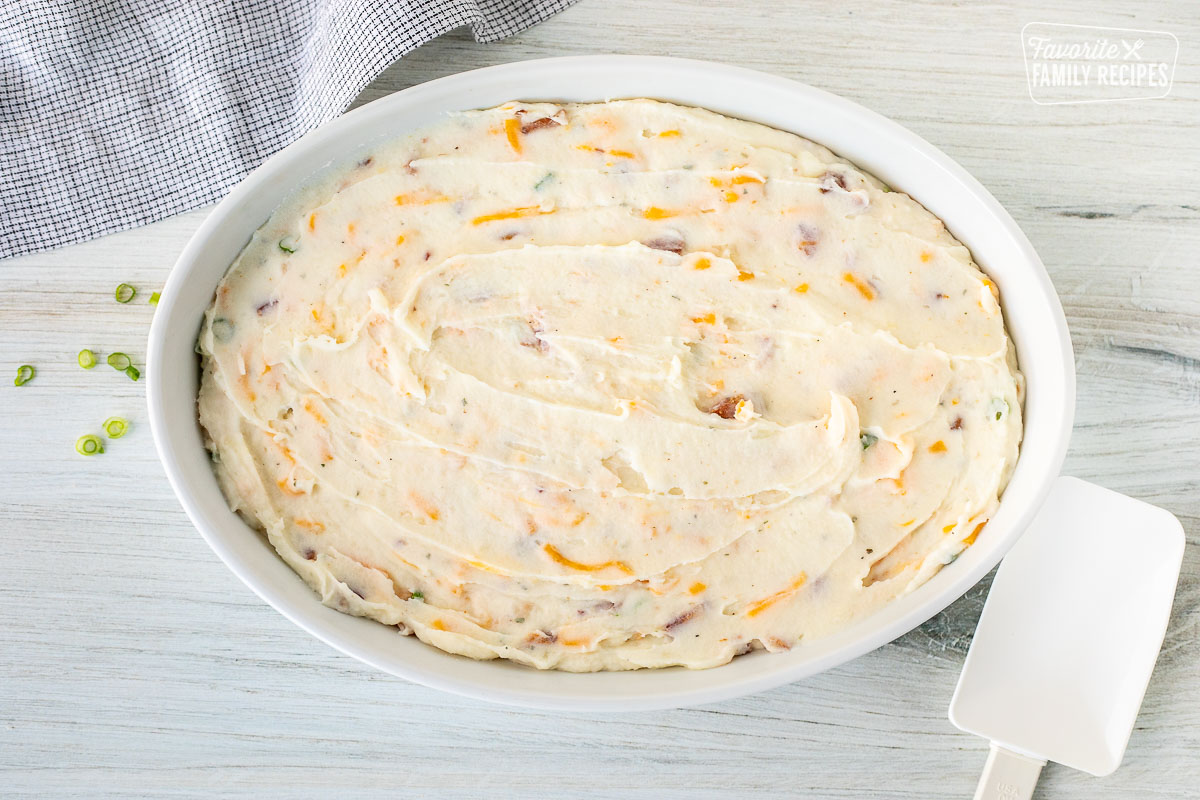 Baking dish with loaded mashed potato mixture. Spatula on the side.