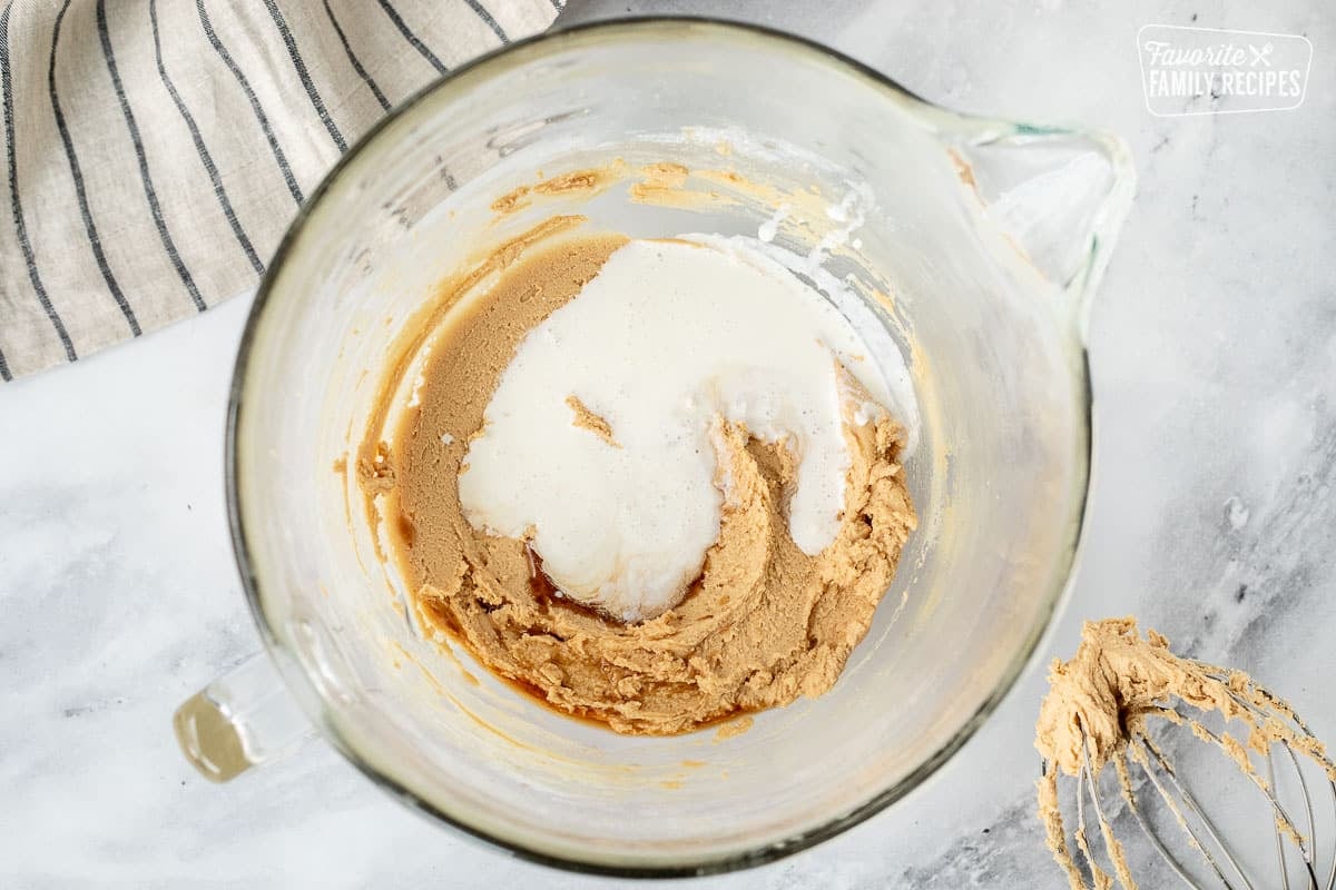 Mixing bowl with cream, vanilla and salt added to peanut butter frosting mixture.