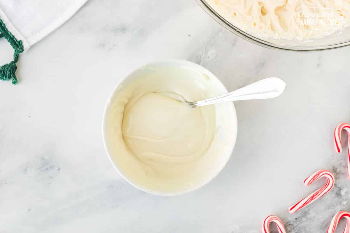 Melted white chocolate chips in a bowl with a spoon.