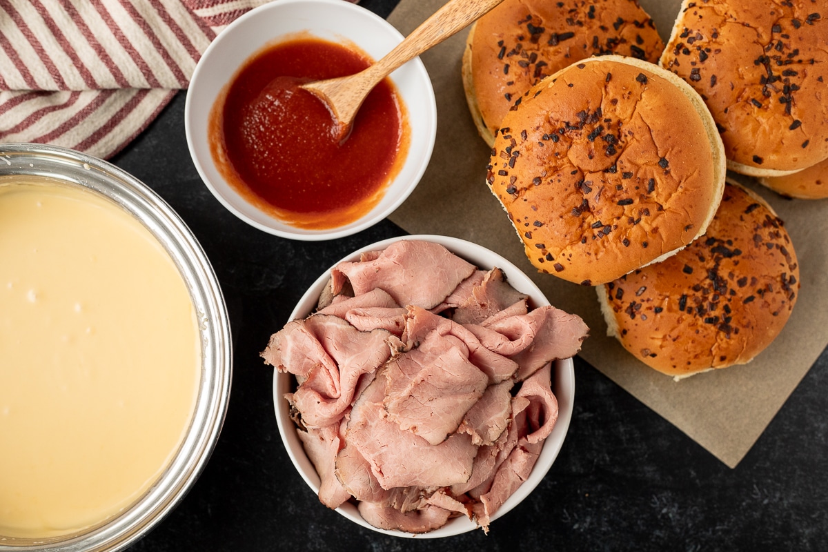 Arby's Beef and Cheddar ingredients including roast beef, red sauce, onion buns and cheddar cheese sauce.