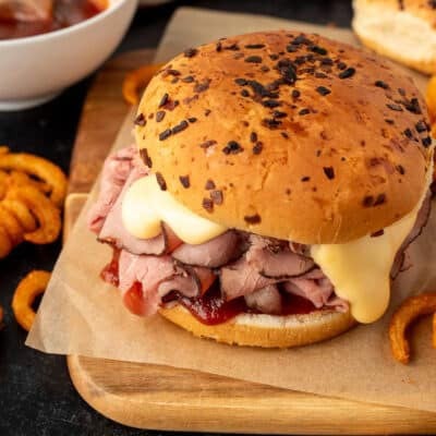 Top view of an Arby's Beef and Cheddar sandwich with an onion bun. Curly fries on the side.