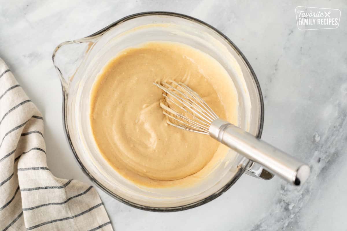 Mixing bowl with batter for Peanut Butter Pancakes with a whisk.