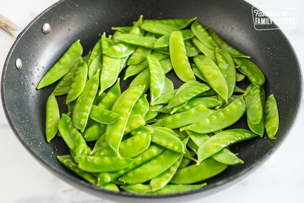 snow peas sautéing in a pan