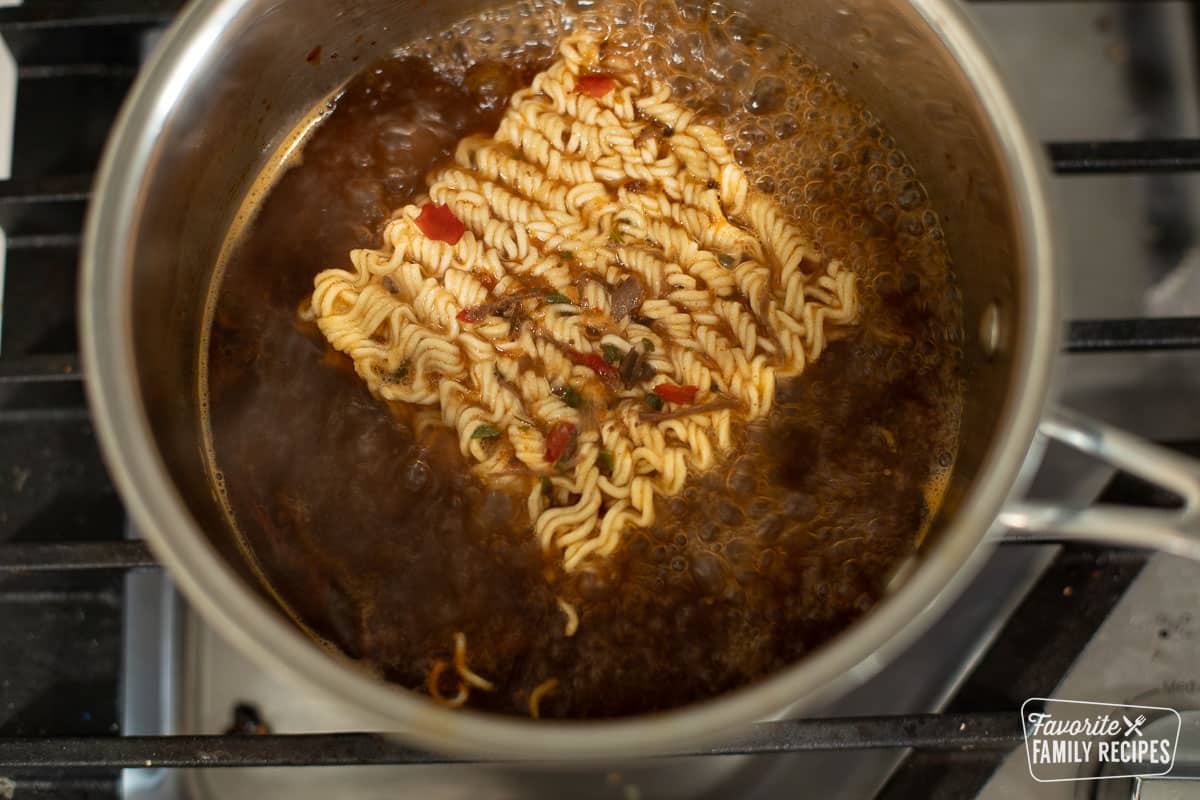 Ramen noodles being cooked in birria broth
