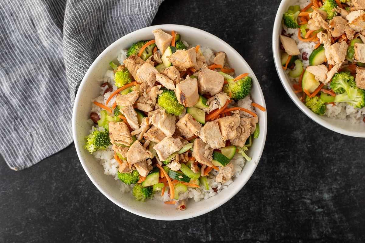 Two rice bowls topped with cut grilled chicken.