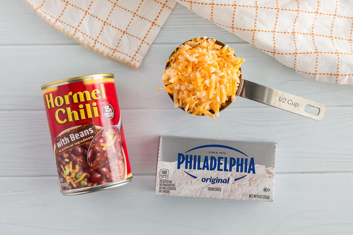 ingredients for chili cheese dip including cream cheese, chili, and colby jack cheese