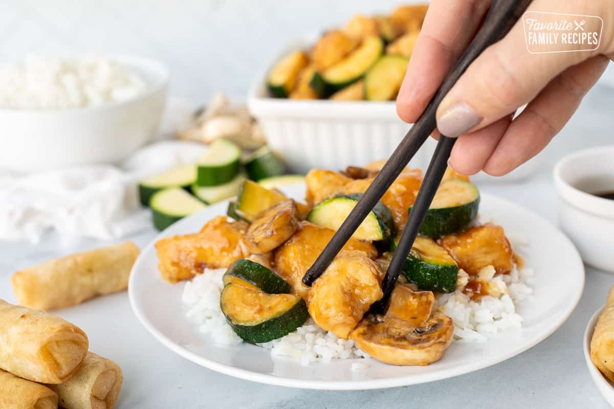 Hand with chopsticks picking up a piece of Panda Express Mushroom Chicken.