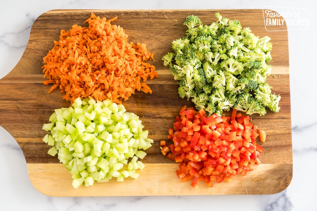 chopped up carrots, broccoli, cucumber, and red pepper on a cutting board