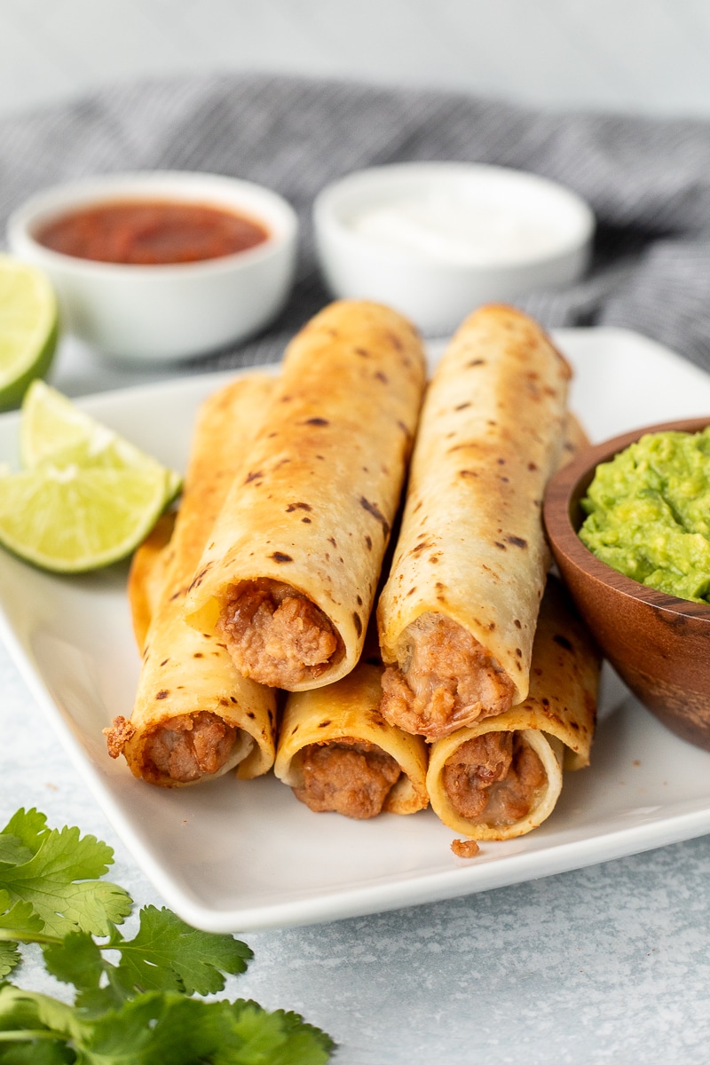 Five crisp bean burritos with guacamole, sour cream and salsa.