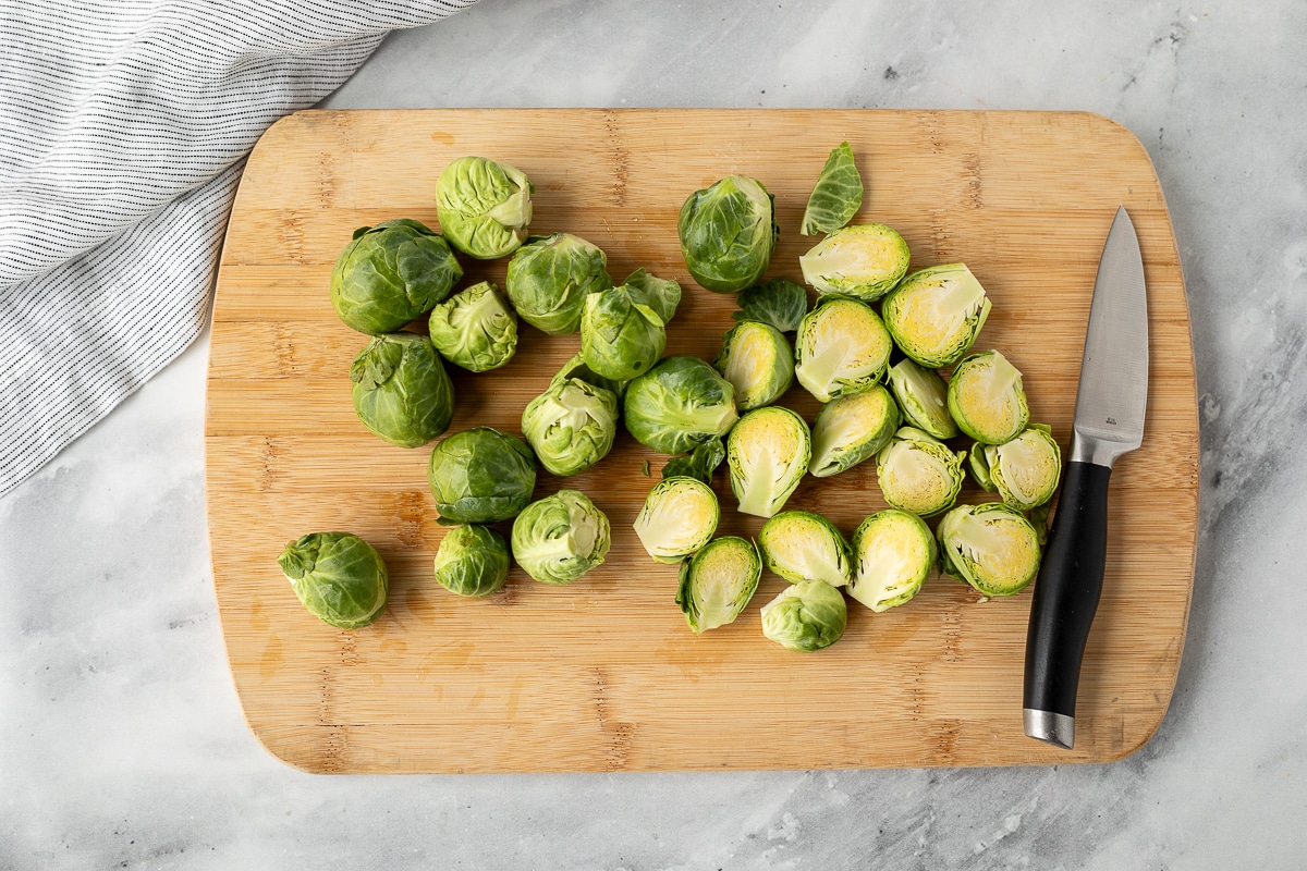Cutting board with cut and trimmed Brussels sprouts.