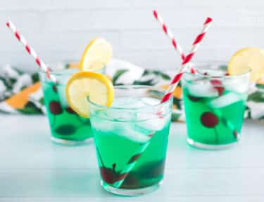 Three cups of mint juleps with cherries and lemon slices