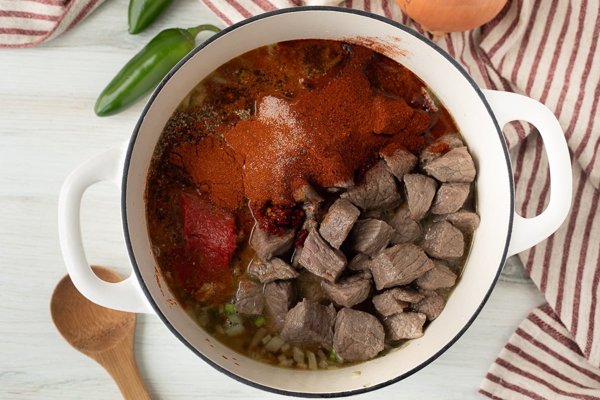 Dutch oven with beef, spices, broth, onions, jalapeños, tomato paste, chipotle pepper and garlic.