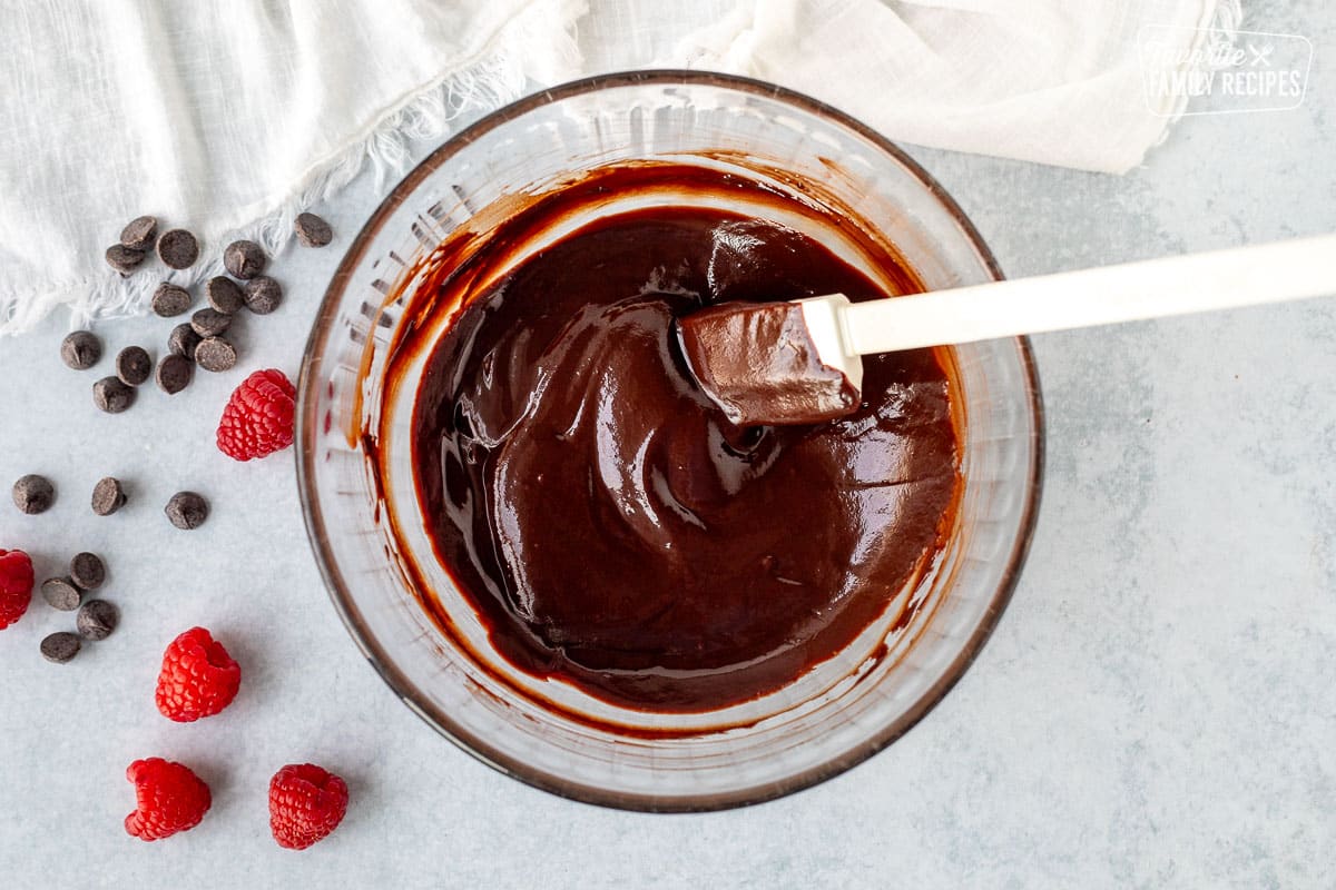 Smooth chocolate ganache in a mixing bowl with a spatula.