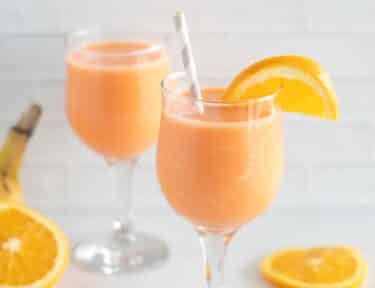 Two glasses of golden detox smoothie with orange slices
