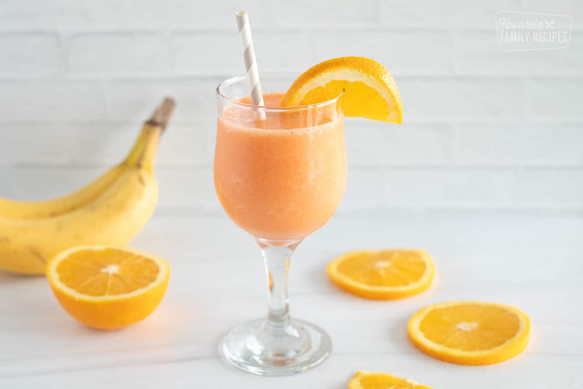 A Glass of golden detox smoothie with orange slices and bananas