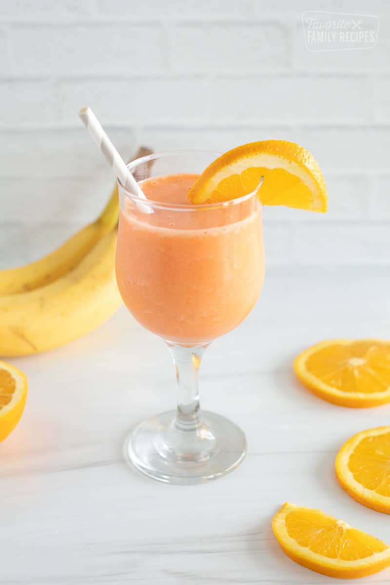 A Glass of golden detox smoothie with orange slices and bananas