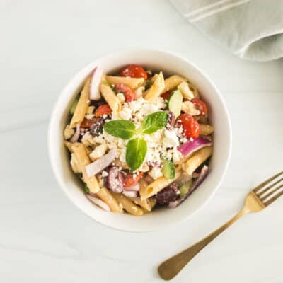 greek pasta salad in a bowl with a fork