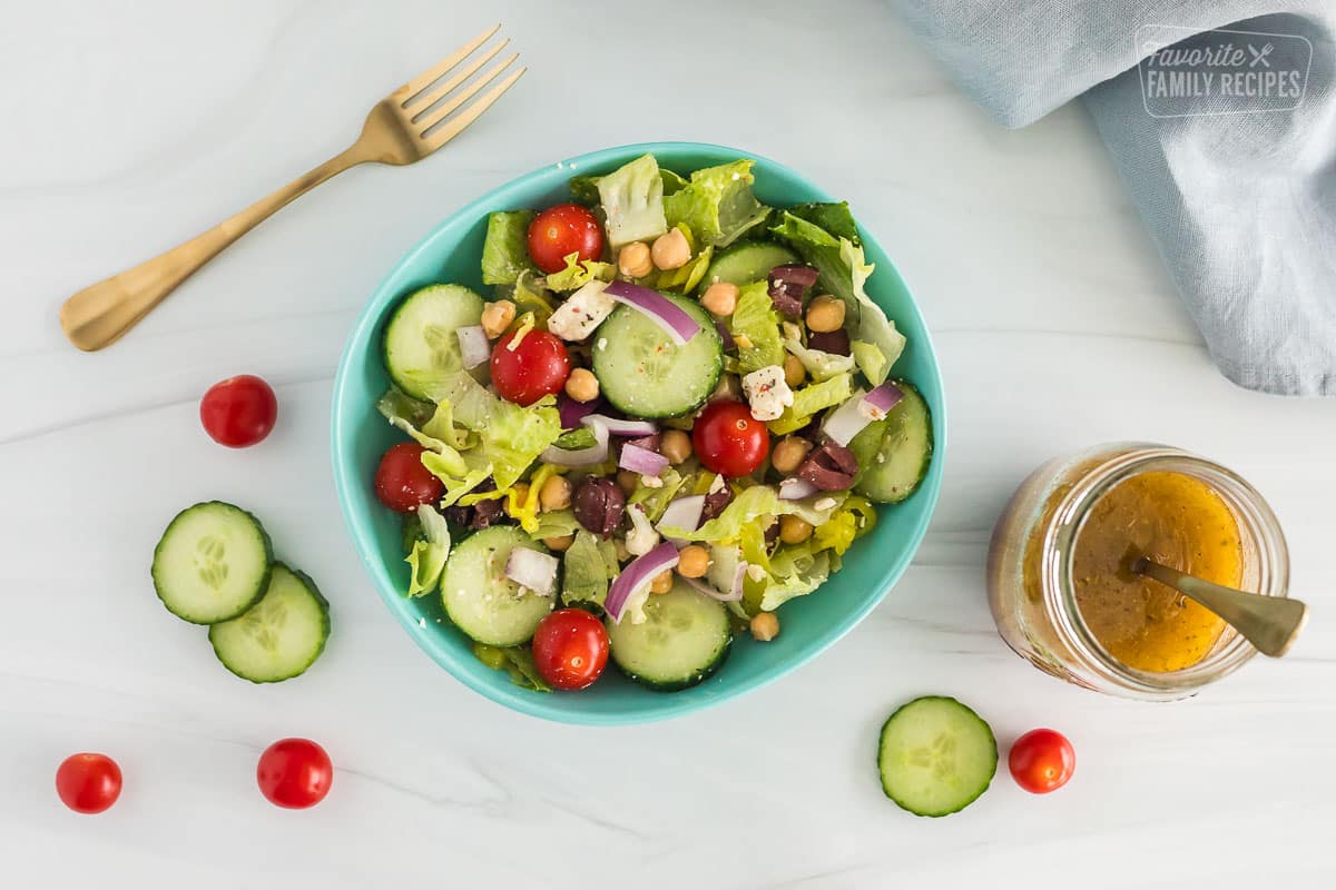 a bowl of greek salad with dressing on the side