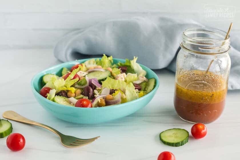 a bowl of greek salad with dressing on the side