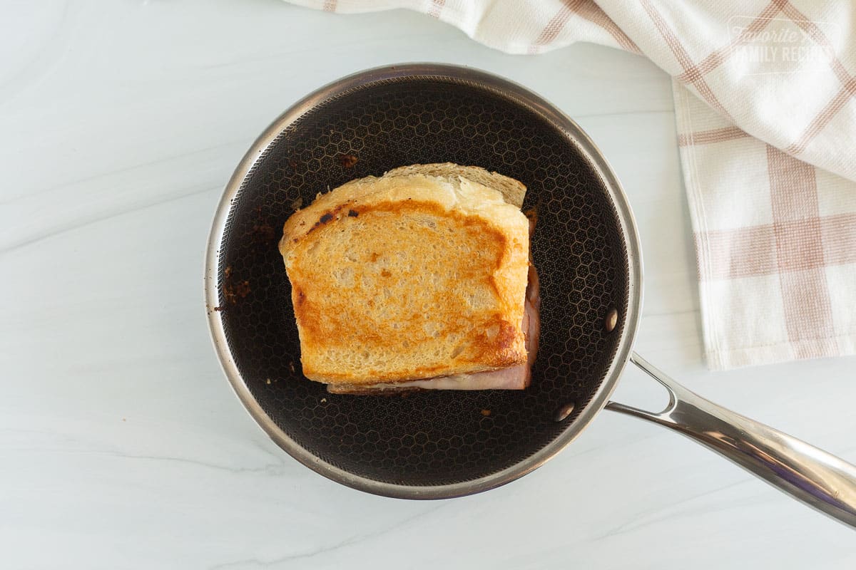 A grilled ham and cheese sandwich on a skillet