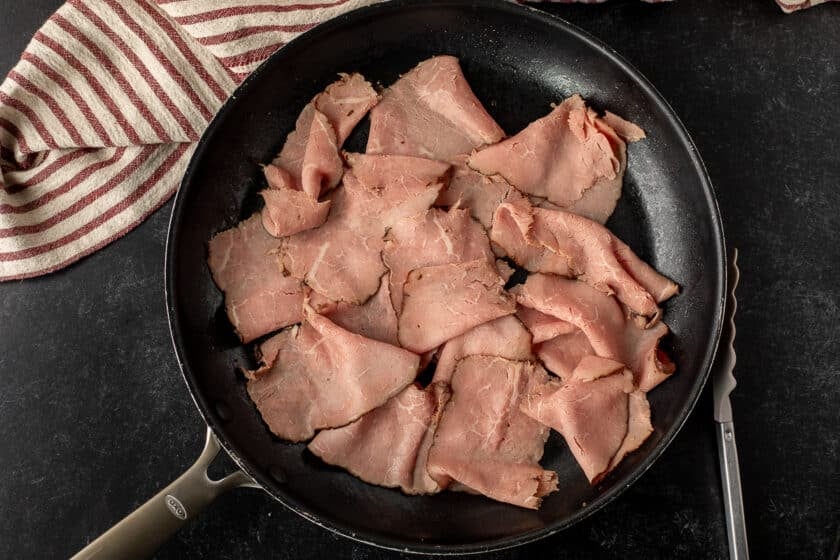 Skillet of heated roast beef for Arby's Beef and Cheddar.