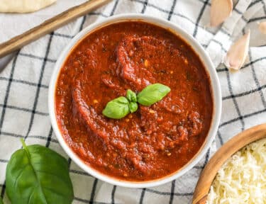 A bowl of homemade pizza sauce topped with basil leaves