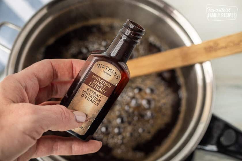 Bottle of Imitation Maple Extract over the pan of boiling maple syrup.