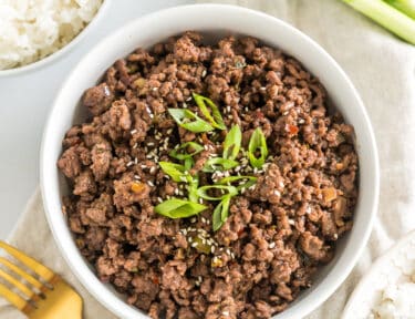 A bowl of seasoned cooked ground meat topped with green onions and sesame seeds