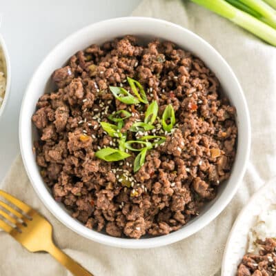 A bowl of seasoned cooked ground meat topped with green onions and sesame seeds