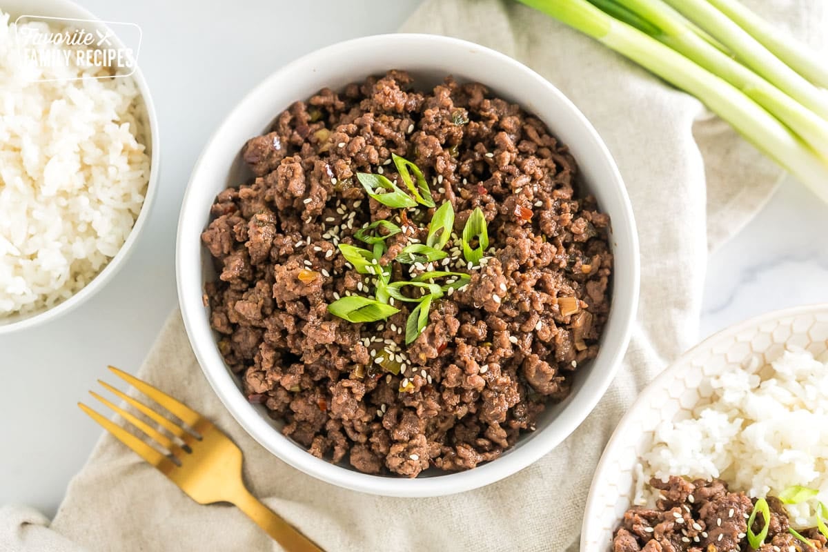 A bowl of seasoned cooked ground meat topped with green onions and sesame seeds