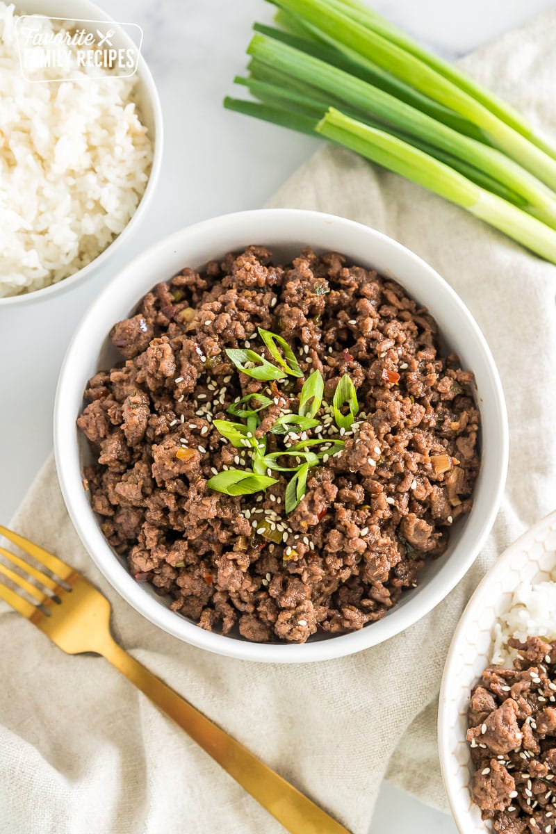 A bowl of seasoned cooked ground meat topped with green onions and sesame seeds.