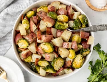 Large bowl of Roasted Potatoes and Brussels Sprouts with a spoon.