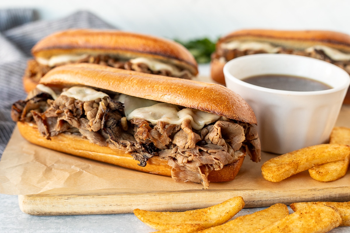 French Dip Sandwich loaded with roast beef and melted provolone cheese. French fries on the side.