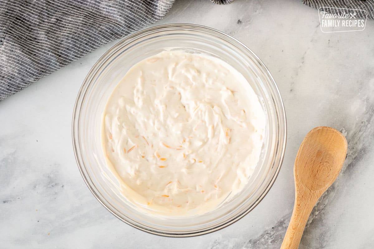 Mixing bowl of Warm Bacon Cheese Dip with a wooden spoon.
