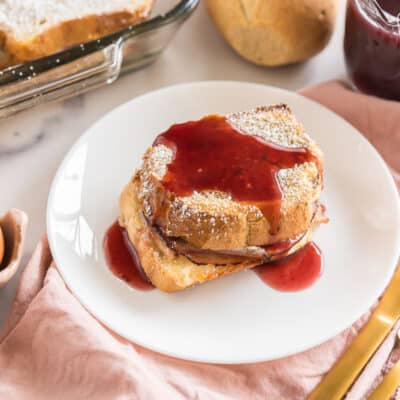 A slice of monte cristo casserole on a plate topped with berry syrup